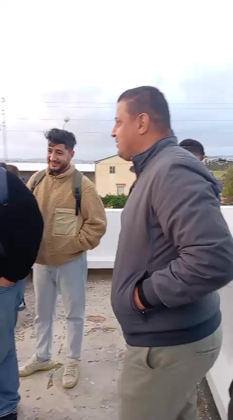 يتجمع الناس في مكان مفتوح، على ما يبدو منخرطين في مراقبة الهلال لشهر رمضان. ويبدو أن الرجل الموجود على اليمين ينظر نحو شيء ما خارج نطاق الكاميرا. بينما يبتسم رجل آخر يحمل حقيبة ظهر.